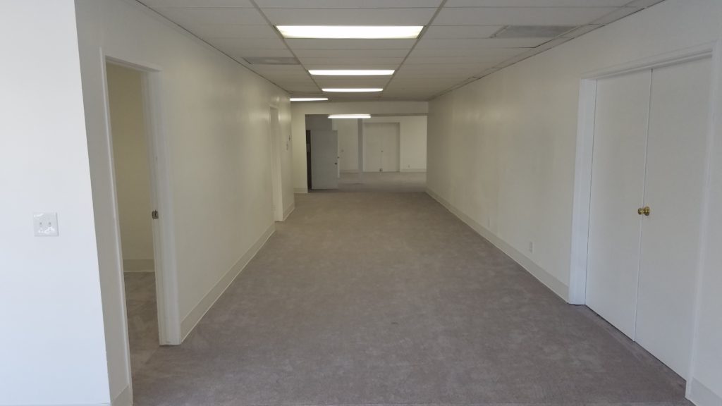 A long hallway with white walls and beige carpet.