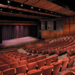 A large auditorium with rows of red seats.